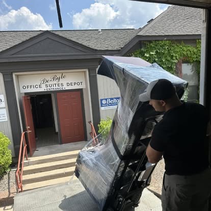 A Peak Movers team member wheeling wrapped office furniture into an office suite