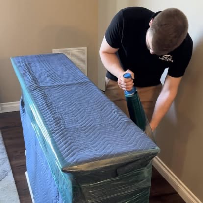 A Peak Movers team member carefully wrapping a dresser in moving blankets