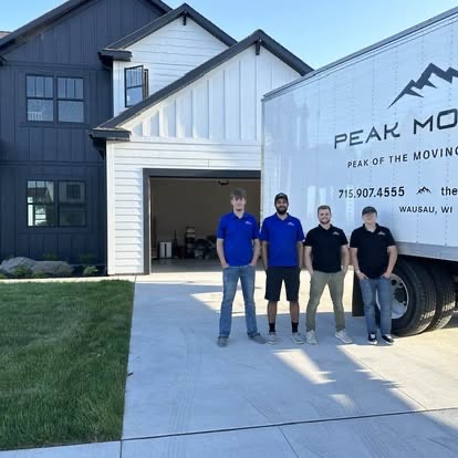 The Peak Movers crew standing together in front of their moving truck and a Wisconsin home